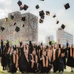 Smiling Graduates Throwing Up Academic Hats near UNAM Central Library Building